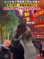 女子在街上搂着黑人男友求喂水，男子似乎一脸嫌弃看着对方……