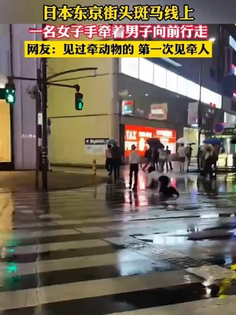 日本东京街头斑马线上，一名女子手牵着男子向前行走！