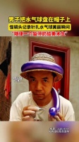 男子把水气球盘在帽子上，慢镜头记录针扎水气球美丽瞬间…
