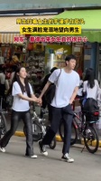 男生拉着女生的手漫步在街头 女生满脸宠溺地望向男生