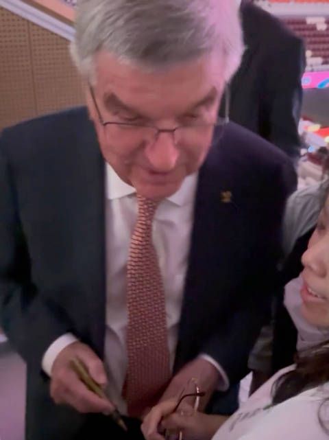 巴赫主席很认真给孙颖莎球迷签名,签在了“莎莎下巴”上