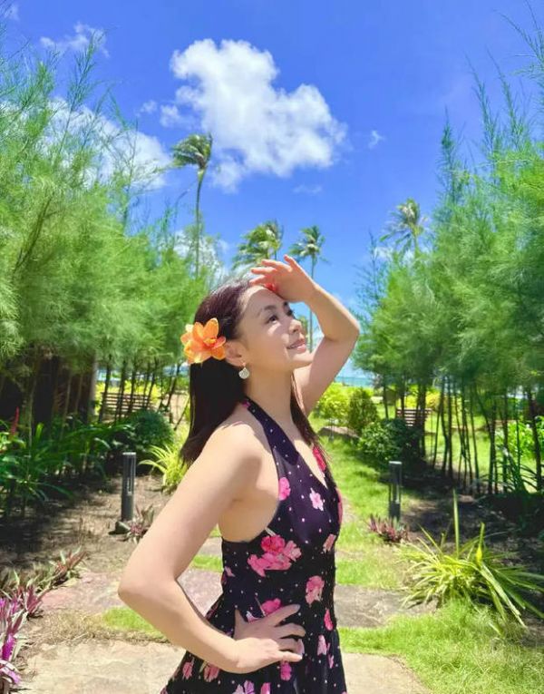 钟欣潼穿碎花挂脖裙，发别橙花，手搭额头眺望。