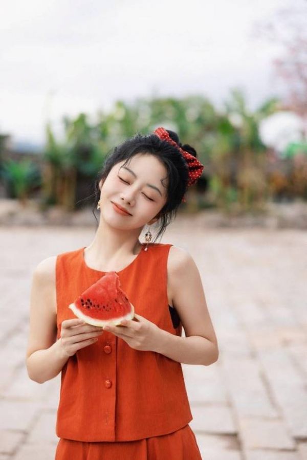 搜狐娱乐讯 8月26日，谭松韵的一组美照爆出，图中，谭松韵穿着红色连衣裙，手拿西瓜，双眼轻闭，表情娇俏可爱。
