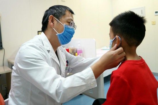 北京儿童医院呼吸中心主任医师秦强在门诊为患儿查体。（受访者供图）