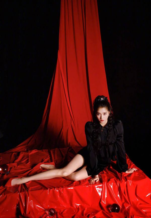 关晓彤坐在红色背景布上，眼神清冷。