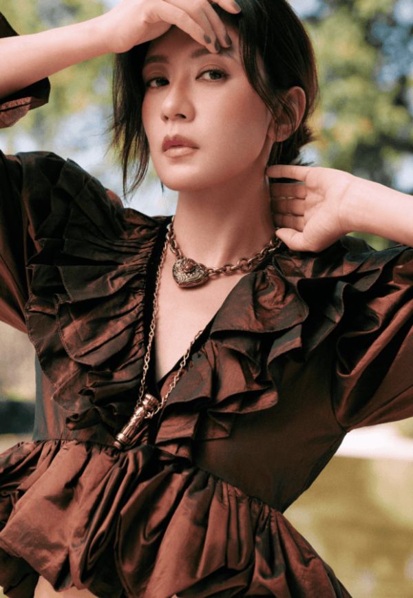 贾静雯手抵额头挡光，阳光铺在身上，氛围感松弛又亮眼。