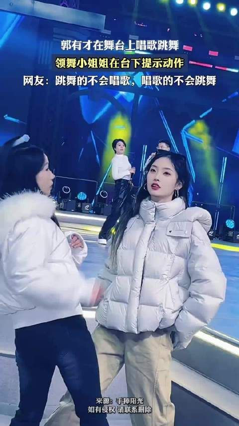 郭有才在舞台上唱歌跳舞，领舞小姐姐在台下提示动作