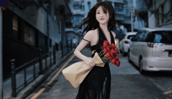 祝绪丹手拿玫瑰站在街边,发丝随风飘扬。