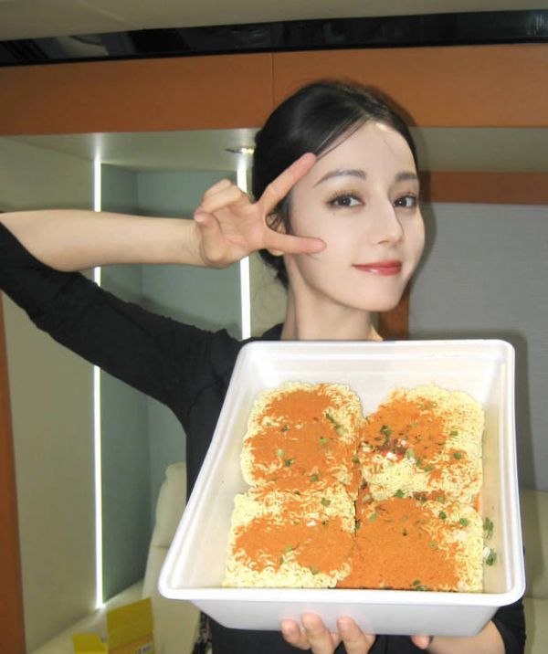迪丽热巴举着泡面拍照,心情愉悦。