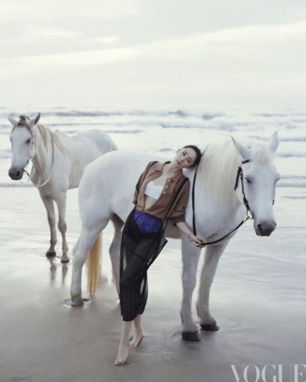 杨幂轻靠白马身侧，姿态放松自然。