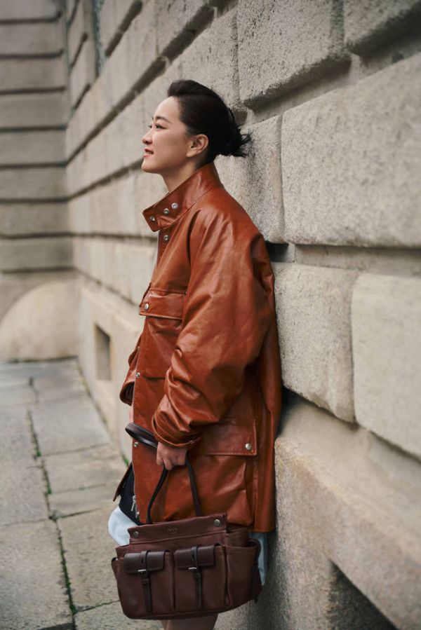 贾玲穿棕皮衣靠墙，侧颜状态松弛又自在。