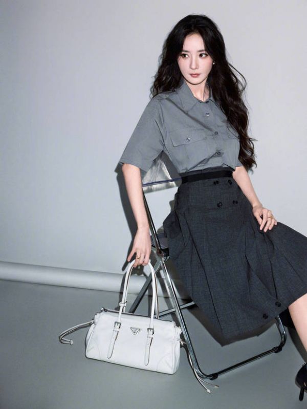 杨幂倚椅而坐,手搭白包神态从容。