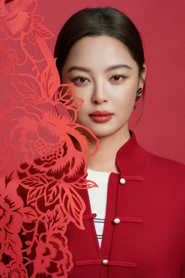 辛芷蕾半遮于剪纸后，眼神沉静。