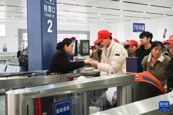 2月22日，来自黔东南州各区县的外出务工人员及家属在凯里南站检票进站。新华社发（邵健摄）