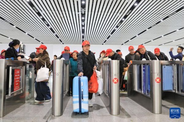 2月22日，乘坐返岗务工专列的务工人员及家属从凯里南站检票进站。新华社发（王波摄）