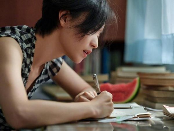 倪妮伏案书写，神态温柔治愈。