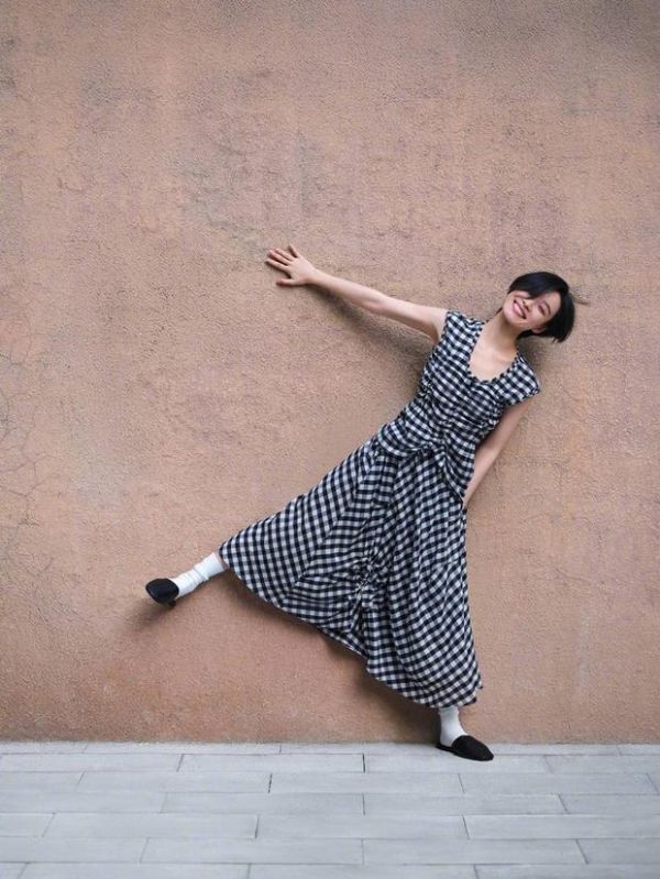 倪妮靠墙摆拍，格纹裙活力满满。