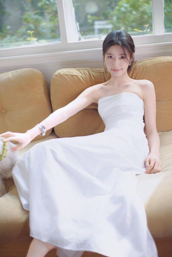 卢昱晓坐沙发逗宠,笑容清甜。