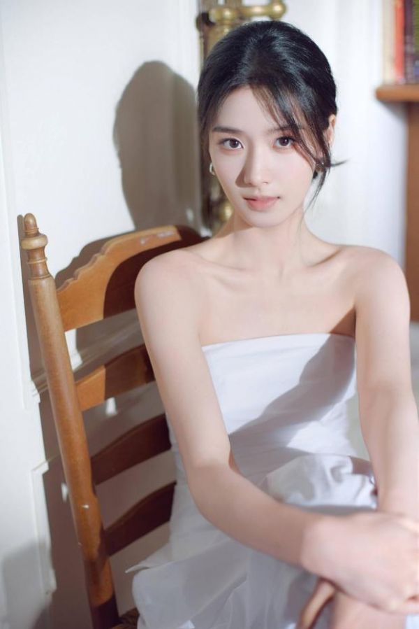 卢昱晓坐木椅上,直视镜头。