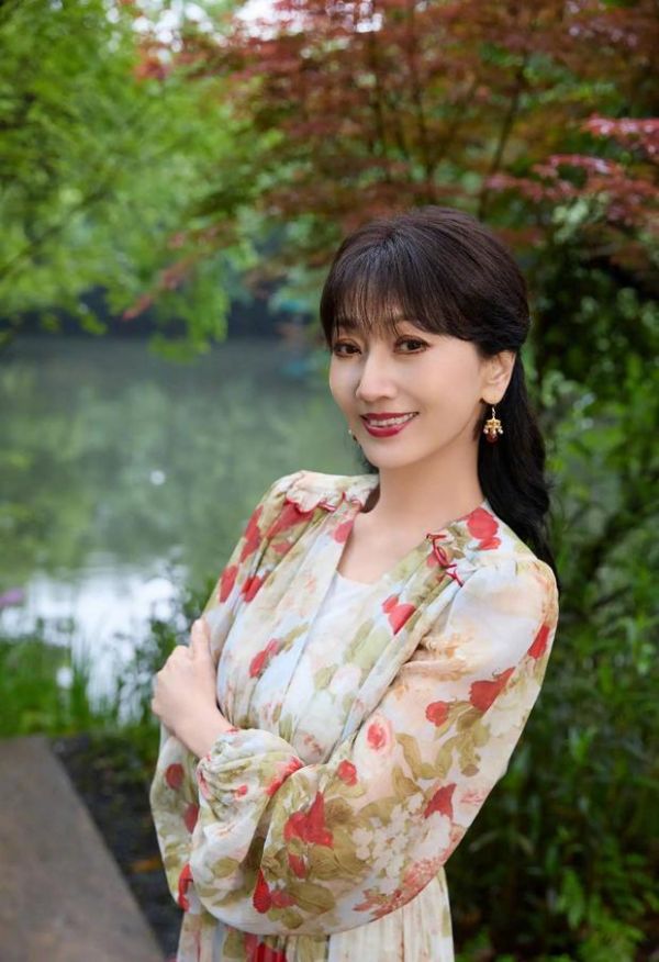 赵雅芝与湖水、绿植同框合影，画面清新怡人。