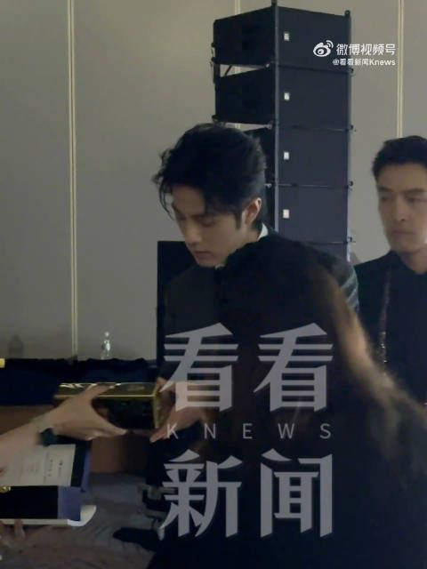 肖战双手将奖杯递给同伴