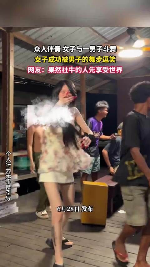 众人伴奏 女子与一男子斗舞，女子成功被男子的舞步逗笑