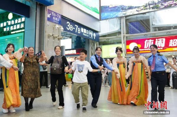 图为云南昆明,昆明站举行暑运活动,工作人员与旅客牵手跳舞,开启美好旅途。中新社记者 刘冉阳 摄