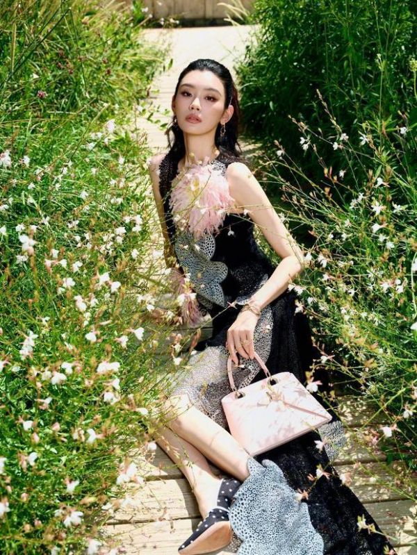 奚梦瑶侧坐在花丛中。