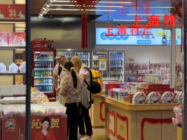 国庆假期,外国游客在上海虹桥火车站内购买上海特产。新华社发(陈晨 摄)